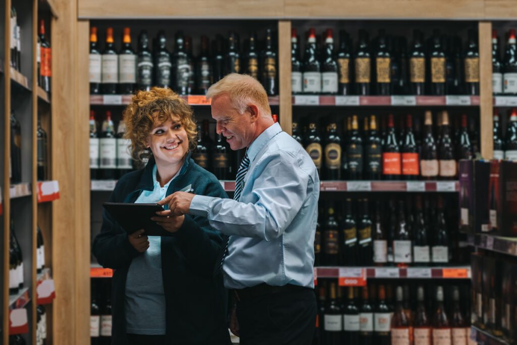 A man and woman working together on an iPad in a liquor store.