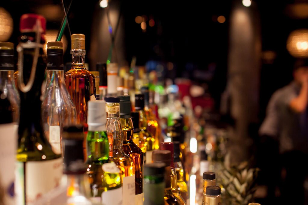 Several bottles of alcohol on the shelf at a bar with dim lighting. Alcohol regulations.
